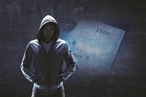 Picture of person in dark hoodie and a washed check behind him.