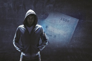 Suspicious man in grey hoody against a dark background with an image of a check alluding to the fact that he might be altering it.