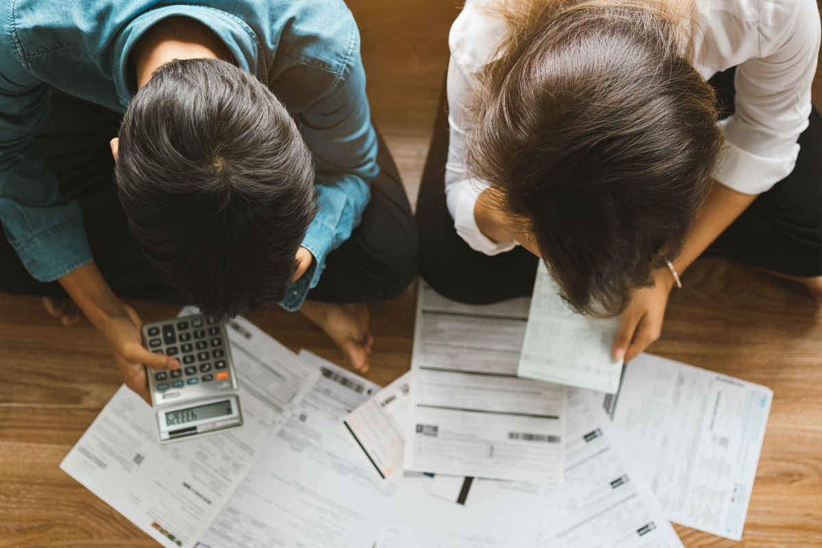 a couple on the floor with a calculator looking at their finances and budgeting for tax season