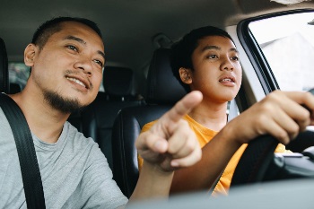 Man teaching teenager how to drive car