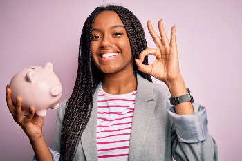Teenage girl holding piggy bank and doing okay symbol